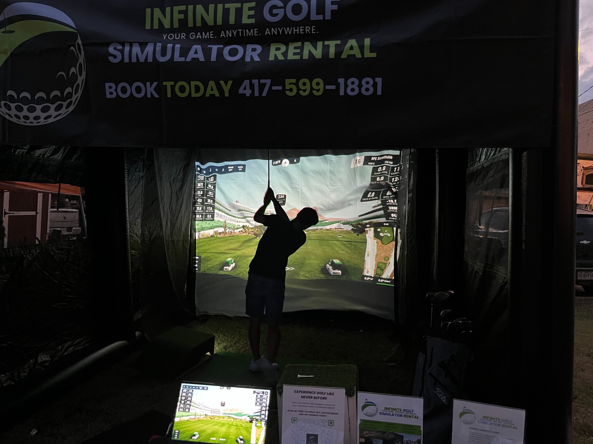 Guest taking a swing at a branded evening fundraiser simulator setup
