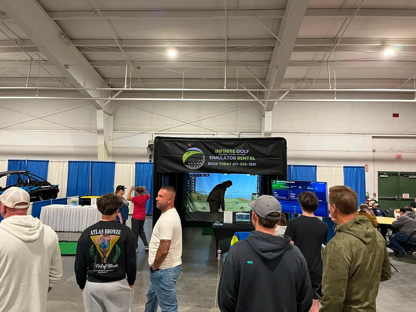 Infinite Golf simulator operating at the Ozark Empire Man Show Expo with guests gathered around the enclosure.