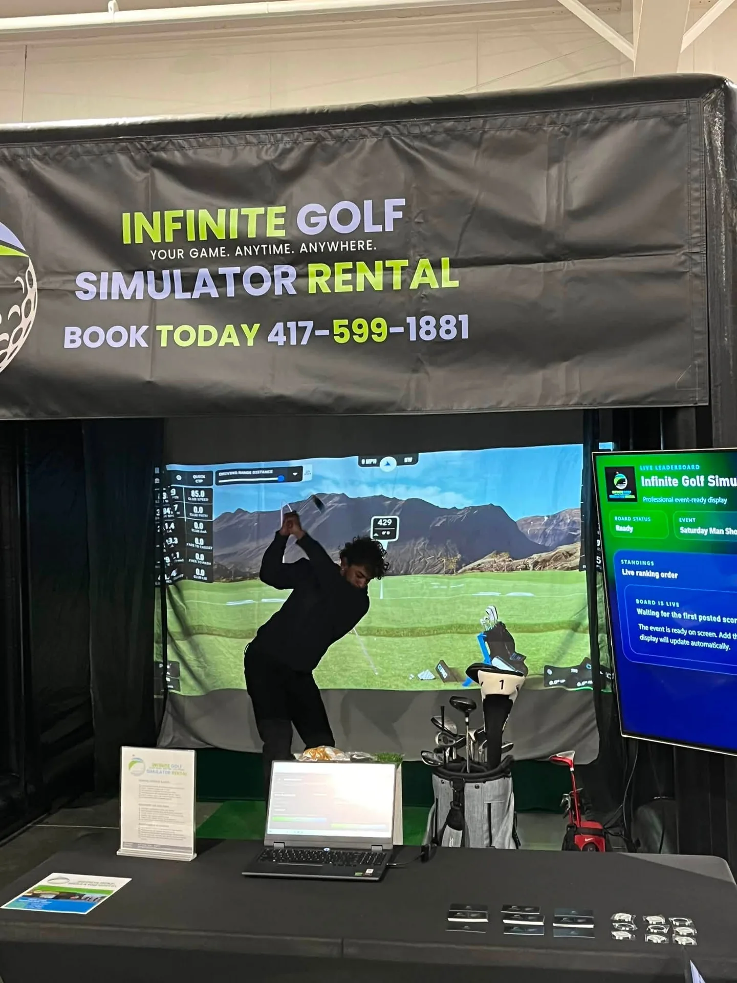 A guest takes a swing inside the Infinite Golf simulator beside the event display at the Ozark Empire Man Show Expo.