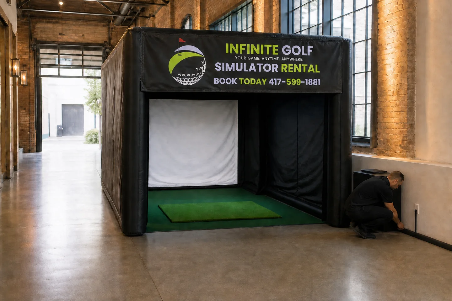 Representative event staff checking a venue power connection beside the Infinite Golf enclosure